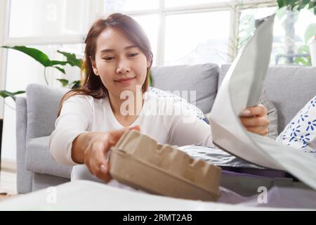 Les femmes asiatiques séparent les ordures à la maison. jeune femme triant et recyclant le plastique, le papier, la canette en aluminium et le récipient de nourriture aux poubelles dans le salon Banque D'Images