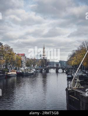 Amsterdam, pays-Bas - novembre 28 2022 : vue le long d'un canal d'Amsterdam vers la tour Montelbaanstoren en automne. Banque D'Images