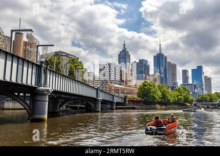 Melbourne, Australie - 22 janvier 2023 : pont sur la rivière Yarra, avec des gens sur les promenades en bateau de plaisance, et les bâtiments modernes de la ville au-delà. Banque D'Images