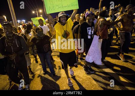 Des manifestants défilent dans la rue pour protester contre le meurtre par la police de Michael Brown, 18 ans, et d’un autre homme noir de 23 ans à Ferguson, Missouri, États-Unis, le 19 août 2014. Un homme de 23 ans a été tué par balle après avoir brandi un couteau sur des policiers dans le nord de St. Louis mardi, les autorités locales ont dit. ) (Dzl) US-MISSOURI-FERGUSON-PROTEST-CLASH TingxShen PUBLICATIONxNOTxINxCHN un manifestant marche DANS la rue pour protester contre le meurtre par la police de Michael Brown, âgé de 18 ans, et d'un autre Noir de 23 ans à Ferguson Missouri, États-Unis, LE 19 2014 août a 23 Banque D'Images