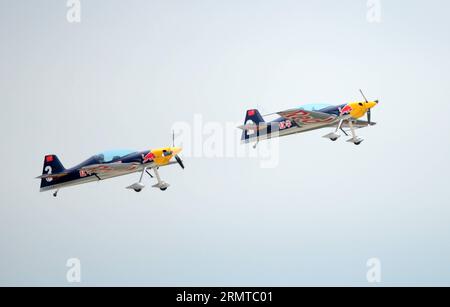 Deux avions du Red Bull Aerobatic Team volent en formation lors d'un entraînement à Faku, dans la province du Liaoning au nord-est de la Chine, le 25 août 2014. L équipe aérienne Red Bull de Chine, la première équipe de voltige illimitée du pays, a été fondée par le pilote professionnel Zhao Wei le 20 septembre 2013. Outre Zhao, les membres de l'équipe sont tous originaires d'Afrique du Sud. L'équipe dispose de quatre avions XA 42, les avions acrobatiques de haut niveau qui permettent à un pilote de voler à des altitudes beaucoup plus basses et à des vitesses plus lentes et donc d'offrir un impact visuel beaucoup plus fort aux spectateurs. L'équipe de voltige se prépare pour le World Advanced Aeroba Banque D'Images