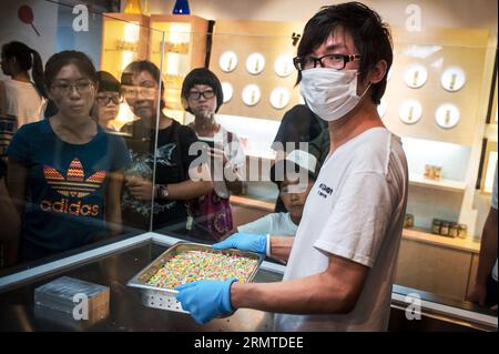 Chen Jingchao détient des bonbons rock australiens finis à Yoo Candy à Beijing, capitale de la Chine, le 29 août 2014. En tant que chef de confiserie de Yoo Candy, un magasin de confiseurs à Nanluoguxiang de Pékin, le travail de Chen Jingchao est de produire des bonbons faits à la main frais avec ses apprentis. Ancien professionnel DE L'INFORMATIQUE à Shanghai dans l'est de la Chine, le jeune homme de 24 ans a commencé à apprendre la confection de bougies en 2013 et a décidé de poursuivre sa carrière à Pékin en mai. Le produit à succès de Yoo Candy est le rock australien , un bonbon dur cylindrique avec un motif sur ses deux extrémités. Chen peut faire environ 50 motifs sur le A. Banque D'Images