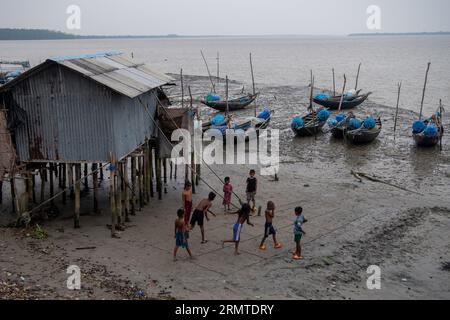 26 août 2023, Khulna, Bangladesh : des enfants sont vus jouer le long de la rive brisée de la rivière Shibsha à Dakop Upazilla, Khulna. Il n'y a pas si longtemps, Kalabogi, un village côtier du Bangladesh, était plein de terres cultivables jusqu'à ce que la montée du niveau de la mer commence à envahir la région jusqu'au golfe du Bengale. De fréquents cyclones et inondations frappent le village depuis la fin des années 1990 En 2009, un cyclone majeur nommé Aila a détruit les 1 400 kilomètres de remblais du pays, 8 800 kilomètres de routes et environ 3 50 000 acres de terres agricoles. Plusieurs centaines de personnes auraient été tuées dans la disa Banque D'Images