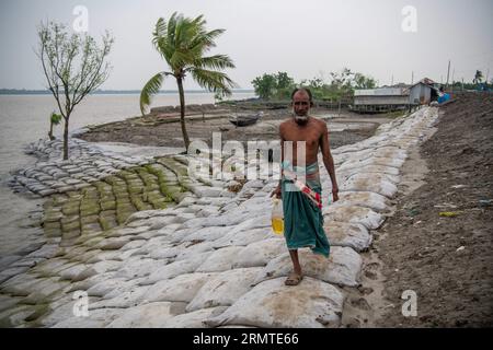 Le 26 août 2023, Khulna, Bangladesh : un homme marche le long d’une zone boueuse près du barrage endommagé de la rivière après de fortes pluies à Kalabogi dans Khulna. Il n'y a pas si longtemps, Kalabogi, un village côtier du Bangladesh, était plein de terres cultivables jusqu'à ce que la montée du niveau de la mer commence à envahir la région jusqu'au golfe du Bengale. De fréquents cyclones et inondations frappent le village depuis la fin des années 1990 En 2009, un cyclone majeur nommé Aila a détruit les 1 400 kilomètres de remblais du pays, 8 800 kilomètres de routes et environ 3 50 000 acres de terres agricoles. Plusieurs centaines de personnes auraient été tuées à Th Banque D'Images