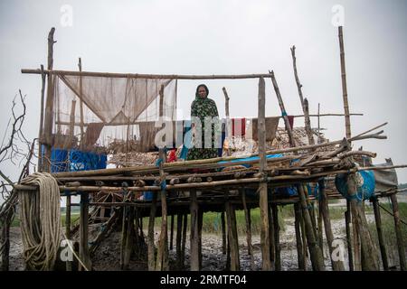 26 août 2023, Khulna, Bangladesh : Mohiful Begum, 35 ans, pose pour une photo devant sa maison endommagée dans une zone côtière à Kalabogi. Il n'y a pas si longtemps, Kalabogi, un village côtier du Bangladesh, était plein de terres cultivables jusqu'à ce que la montée du niveau de la mer commence à envahir la région jusqu'au golfe du Bengale. De fréquents cyclones et inondations frappent le village depuis la fin des années 1990 En 2009, un cyclone majeur nommé Aila a détruit les 1 400 kilomètres de remblais du pays, 8 800 kilomètres de routes et environ 3 50 000 acres de terres agricoles. Plusieurs centaines de personnes auraient été tuées Banque D'Images