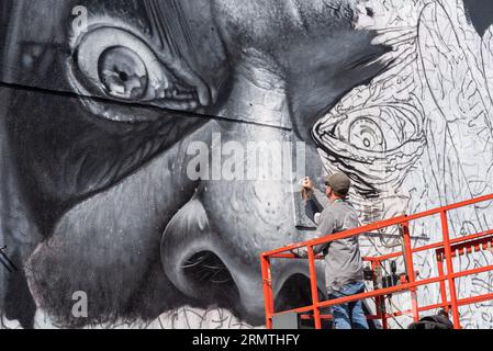 Southend on Sea, Essex, Royaume-Uni. 30 août 2023. Présenté comme le plus grand festival d'art de rue d'Europe, Southend continue de célébrer son nouveau statut de ville avec l'événement City Jam. Plus de 200 artistes de rue locaux, nationaux et internationaux exposent leurs compétences dans 100 endroits du centre-ville. Quelques murs temporaires ont été érigés, mais les artistes décorent également les côtés des bâtiments et autres structures permanentes. Devant se dérouler du premier au troisième septembre, les artistes ont commencé à travailler sur les plus grandes peintures murales afin d'être prêts pour l'événement. Artiste masculin travaillant sur une grande murale de visage Banque D'Images
