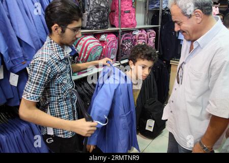 (140913) -- DAMAS, 13 septembre 2014 -- Un élève syrien essaie de porter son uniforme scolaire à Damas, Syrie, le 13 septembre 2014, un jour avant le début de la nouvelle année scolaire dans ce pays déchiré par la guerre. Quelque 4,5 millions d’élèves syriens iront à leurs écoles le 14 septembre, malgré l'autorisation du président américain Barack Obama de frappes aériennes américaines en Syrie contre les États islamiques (EI).)(zhf) SYRIE-DAMAS-NOUVELLE ANNÉE SCOLAIRE bassemxtellawi PUBLICATIONxNOTxINxCHN Damas Sep 13 2014 un étudiant syrien tente son uniforme scolaire à Damas Syrie LE 13 2014 septembre un jour avant le début de la nouveau S Banque D'Images