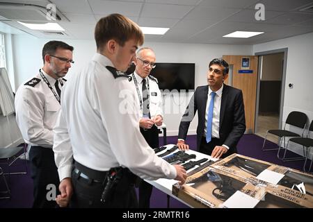 Sir Mark Rowley (deuxième à droite), commissaire de police métropolitaine, et Rishi Sunak, Premier ministre, regardent des couteaux et des machettes saisis lors d'attaques au couteau lors d'une visite au poste de police de Kilburn, au nord-ouest de Londres. Date de la photo : mercredi 30 août 2023. Banque D'Images