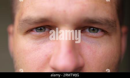 Gros plan extrême de beau visage de jeune homme regardant la caméra et souriant. Émotions positives. Un homme caucasien sourit de bonne humeur. Yeux masculins avec profond Banque D'Images