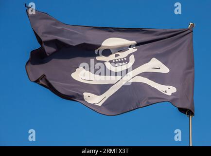 jolly roger. Drapeau de pirate. Sur fond de ciel bleu. Banque D'Images