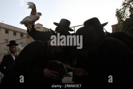 (141001) -- JÉRUSALEM, 1 octobre 2014 -- des Juifs ultra-orthodoxes balancent un poulet blanc au-dessus de leur tête en lisant une prière dans le quartier de Mea Shearim à Jérusalem le 1 octobre 2014, dans le cadre de la cérémonie traditionnelle Kaparot avant le jour le plus sacré du judaïsme, Yom Kippour. Kaparot est une coutume ancienne et mystique liée au jour juif des Expiations, Yom Kippour, et peut être exécutée à tout moment entre Rosh Hashana (nouvel an juif) et Yom Kippour.) MIDEAST-JERUSALEM-YOM KIPPUR GilxCohenxMagen PUBLICATIONxNOTxINxCHN Jerusalem OCT 1 2014 Juifs ultra orthodoxes balancent un poulet blanc sur leur tête Banque D'Images