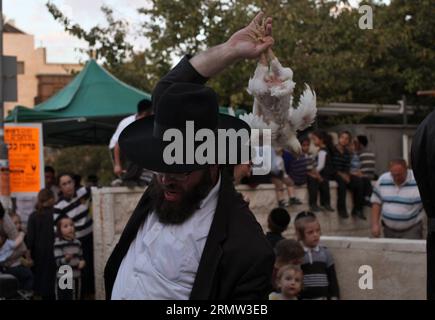 (141001) -- JÉRUSALEM, 1 octobre 2014 -- des Juifs ultra-orthodoxes balancent un poulet blanc au-dessus de leur tête en lisant une prière dans le quartier de Mea Shearim à Jérusalem le 1 octobre 2014, dans le cadre de la cérémonie traditionnelle Kaparot avant le jour le plus sacré du judaïsme, Yom Kippour. Kaparot est une coutume ancienne et mystique liée au jour juif des Expiations, Yom Kippour, et peut être exécutée à tout moment entre Rosh Hashana (nouvel an juif) et Yom Kippour.) MIDEAST-JERUSALEM-YOM KIPPUR GilxCohenxMagen PUBLICATIONxNOTxINxCHN Jerusalem OCT 1 2014 Juifs ultra orthodoxes balancent un poulet blanc sur leur tête Banque D'Images