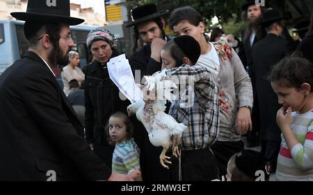 (141001) -- JÉRUSALEM, 1 octobre 2014 -- des Juifs ultra-orthodoxes balancent un poulet blanc au-dessus de leur tête en lisant une prière dans le quartier de Mea Shearim à Jérusalem le 1 octobre 2014, dans le cadre de la cérémonie traditionnelle Kaparot avant le jour le plus sacré du judaïsme, Yom Kippour. Kaparot est une coutume ancienne et mystique liée au jour juif des Expiations, Yom Kippour, et peut être exécutée à tout moment entre Rosh Hashana (nouvel an juif) et Yom Kippour.) MIDEAST-JERUSALEM-YOM KIPPUR GilxCohenxMagen PUBLICATIONxNOTxINxCHN Jerusalem OCT 1 2014 Juifs ultra orthodoxes balancent un poulet blanc sur leur tête Banque D'Images