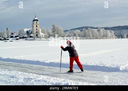 Une femme patinant sur le lac Siljan, église Rättvik en arrière-plan Banque D'Images