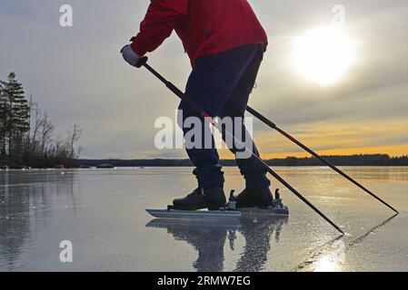 Gros plan des jambes et des bras d'une personne, patinant sur un lac portant des patins nordiques et des bottes Banque D'Images