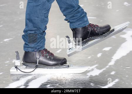 Gros plan des pieds d'une personne, patinant sur un lac portant des patins nordiques et des bottes Banque D'Images