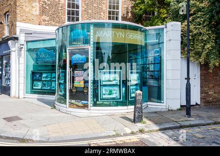 Une branche des agents immobiliers Martyn Gerrard avec un bureau à façade en verre de forme inhabituelle à Kentish Town, Londres, Royaume-Uni Banque D'Images
