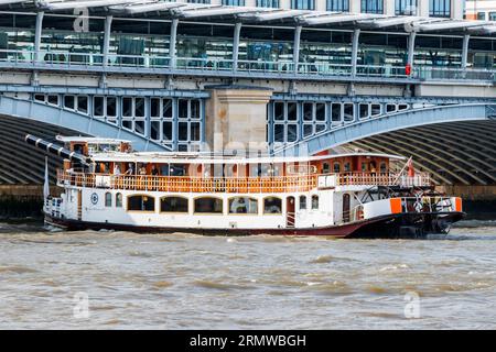 A Thames paddle steamer approaches an arch of Blackfriars railway bridge on the River Thames, its funnel retracted, London, UK Stock Photo
