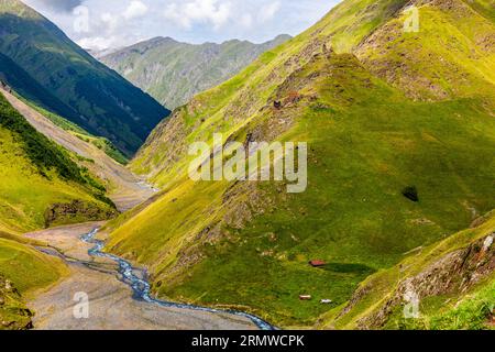 Une haute vallée avec un ruisseau de montagne à Tusheti, au nord-est de la Géorgie. Une tour défensive médiévale sur un éperon rocheux à droite et une cabane alpine au fond de la vallée témoignent de la population clairsemée de cette région éloignée, située à plus de 2 000 mètres d'altitude. Omalo-Dartlo-Girevi, municipalité d'Akhmeta, Kakheti, 0900, Géorgie Banque D'Images