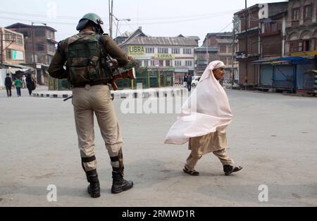 (141023) -- SRINAGAR, 23 octobre 2014 -- un soldat paramilitaire indien monte la garde alors qu'une musulmane cachemirienne passe devant elle lors d'une grève contre la visite du Premier ministre indien Narendra Modi à Srinagar, capitale estivale du Cachemire contrôlé par l'Inde, le 23 octobre 2014. Modi est arrivé jeudi à Srinagar pour célébrer la fête hindoue des lumières avec les personnes touchées par les inondations. Des groupes séparatistes cachemiriens avaient appelé à une grève générale et protesté contre la visite du Modi. (Zjy) KASHMIR-SRINAGAR-INDIA-PM-VISIT JavedxDar PUBLICATIONxNOTxINxCHN Srinagar OCT 23 2014 au paramilit indien Banque D'Images