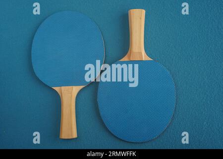 Deux raquettes bleues de tennis de table reposent à l'envers sur un fond bleu avec une vue rapprochée d'en haut. Jeu de loisirs. Équipement de sport. International Banque D'Images