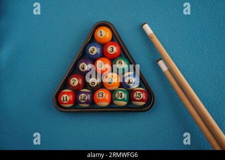 Boules de snooker et queue sur fond bleu. Boules de billard sur le plateau. Table de billard avec support de balles. Mise au point sélective. Boules de billard dans un rack sur a Banque D'Images