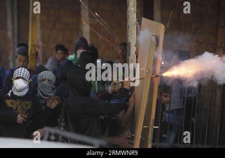 (141106) -- JÉRUSALEM, 6 novembre 2014 -- des jeunes Palestiniens masqués utilisent des portes comme boucliers lors d'affrontements avec les forces de sécurité israéliennes dans le camp de réfugiés palestiniens de Shuafat, Jérusalem-est, le 6 novembre 2014. Le Premier ministre israélien Benjamin Netanyahu a rassuré jeudi le roi Abdallah II de Jordanie qu’Israël n’a pas l’intention de changer le statu quo dans la mosquée al-Aqsa et son complexe à Jérusalem-est, ont déclaré des responsables et des médias locaux. De nouveaux affrontements entre Palestiniens jetant des pierres et police ont éclaté mercredi après qu'un groupe de militants d'extrême droite ait tenté de mener une veillée de prière dans les s. Banque D'Images