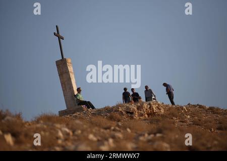 (141112) -- JÉRICHO, 12 novembre 2014 -- Un touriste est assis sous une croix près de la rue orthodoxe grecque Monastère George à Wadi Qelt, près de la ville de Jéricho en Cisjordanie, le 12 novembre 2014. Le complexe suspendu aux falaises du vie siècle, avec son ancienne chapelle et ses jardins, est actif et habité par des moines orthodoxes grecs. Le Wadi Qelt est une vallée qui traverse le désert de Judée en Cisjordanie, d'ouest en est, qui prend naissance près de Jérusalem et se termine près de Jéricho. MIDEAST-JERICHO-WADI-QELT LuayxSababa PUBLICATIONxNOTxINxCHN Jericho nov 12 2014 un touriste est assis sous une croix près de l'orthodoxe grecque St George Mo Banque D'Images