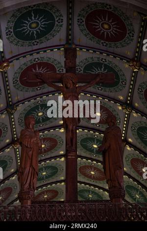 Jésus-Christ sur une croix à l'intérieur d'un bâtiment d'église avec fresque dorée ornementée derrière Banque D'Images