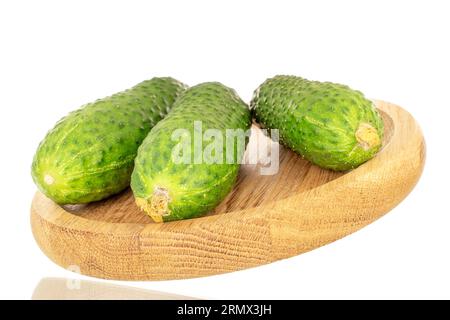 Three fresh pickled cucumbers on a wooden plate, macro, isolated on white background. Stock Photo