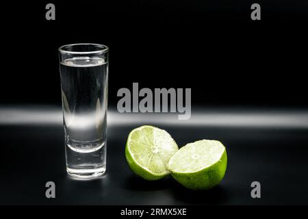 Tequila shot avec citron sur fond noir Banque D'Images