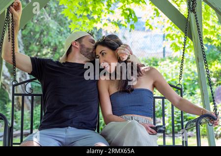 Jeune couple marié profitant d'une balançoire sur une chaude journée d'été Banque D'Images