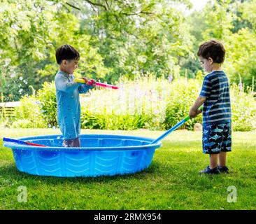 Deux jeunes garçons jouant avec des jouets aquatiques par une chaude journée d'été Banque D'Images