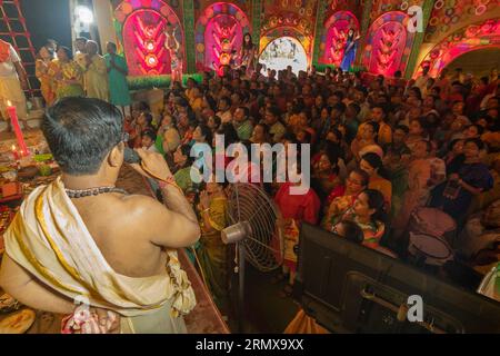 Howrah, Bengale occidental, Inde- 3 octobre 2022 : purohit hindou prononçant des shlokas sanskrit, guidant les dévots pour pushpanjali pour prier et adorer. Banque D'Images