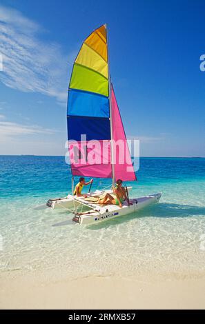 Maldives. Jeune couple naviguant sur un bateau Hobie Catamaran. Banque D'Images