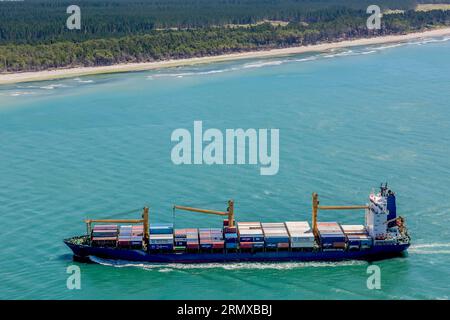 Photo d'un cargo passant un petit détroit près de la ville de Tauranga en Nouvelle-Zélande Banque D'Images