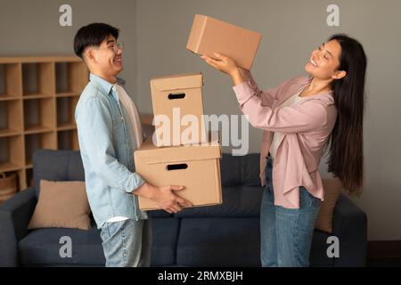 Femme asiatique donnant carton Moving Boxes au mari debout à l'intérieur Banque D'Images