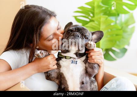 Belle jeune femme caressant embrassant son chien dans un nouvel appartement Banque D'Images
