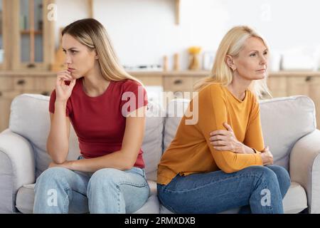 Offended millennial adult daughter and senior mother sit aside Stock Photo