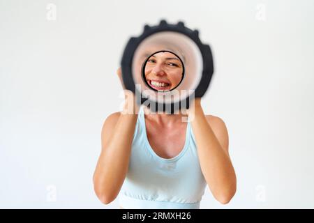Sporty female person looking through foam roller and has fun. Banque D'Images