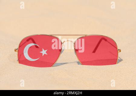 Lunettes de soleil avec des lunettes en forme de drapeau de la Turquie reposent sur le sable. Concept de vacances d'été et de voyages en Turquie. Repos estival. Fêtes de fin d'année Banque D'Images