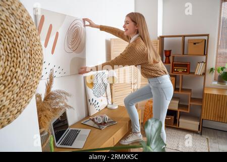 Une jeune femme qui pendait de la peinture sur un mur lumineux à la maison Banque D'Images