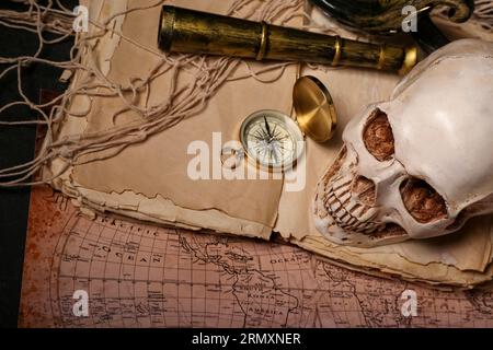 Crâne humain avec espion, vieux manuscrits, carte du monde et boussole sur fond noir Banque D'Images