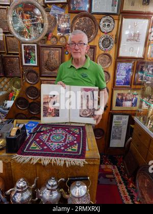 Fier propriétaire d'un Coppersmith Shop rue Kazandžiluk montre un livre avec des photos de la boutique. Ville de Sarajevo, 30 août 2023 Banque D'Images