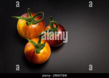 Tomates rayées rouges jaunes humides sur fond noir Banque D'Images