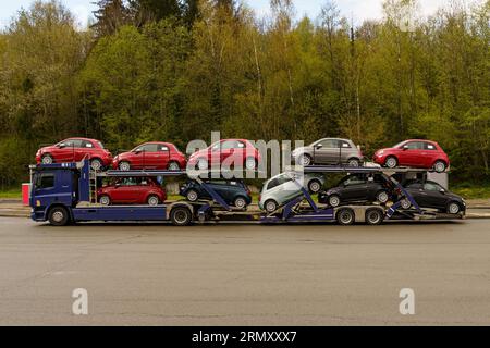 Transporteur de voitures avec de nouvelles voitures garées sur le bord de la route. Transport de voitures neuves. Banque D'Images