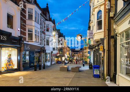 Boutiques, cafés et pubs bordent le principal quartier commerçant de High Street en début de soirée dans la ville historique médiévale de Winchester, Angleterre Banque D'Images