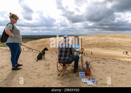 Un artiste avec un chevalet dessine un vieux phare sur un bord de mer sablonneux. Rubjerg Knude FYR, Danemark Banque D'Images