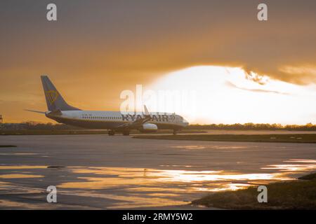 GLASGOW, Royaume-Uni, 24.3,2023. Le Boeing 737 de Ryanair est debout sur une aire de trafic de l'aéroport international avec un beau rétro-éclairage tôt le matin. Banque D'Images