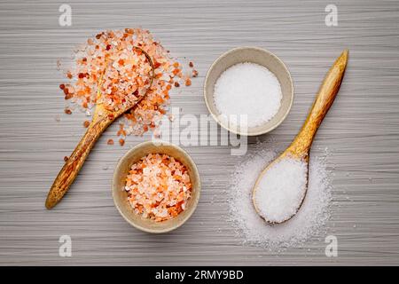 Une photo à plat os gros sel rose de l'Himalaya et gros sel de mer blanc dans des bols et sur des cuillères en bois. Banque D'Images